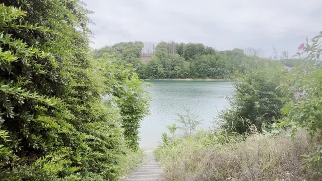 aggertalsperre reservoir in Germany between forest with small stone stairs down to the bank with squalls around it