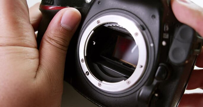 Close-up of a technician clicking the shutter and meticulously checking the sensor of a DSLR camera.