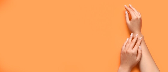 Female hands with beautiful manicure on orange background with space for text - obrazy, fototapety, plakaty