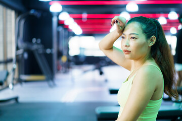 Good looking - beautiful Asian woman relaxing in the gym after made weight training and cardio workout.