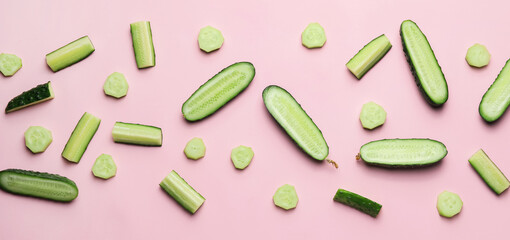 Many cut cucumbers on pink background, top view
