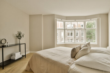 a bedroom with white walls and wood flooring in front of a large window that looks out onto the street