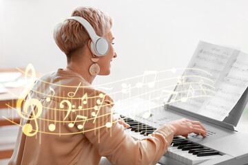 Mature female composer playing synthesizer at home