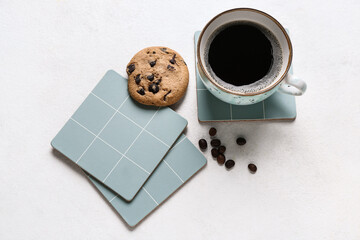 Drink coasters with cup of coffee, cookie and beans on white table