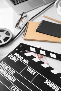 Notebooks with film reel and movie clapper on grey background, closeup