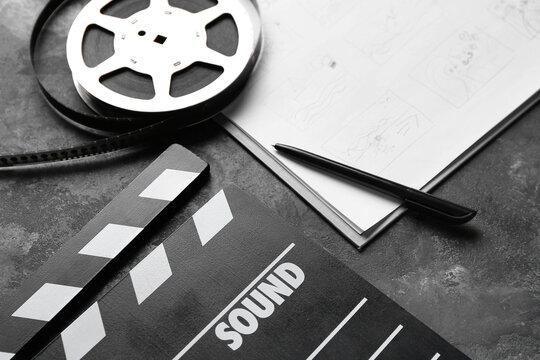 Storyboard with movie clapper and film reel on dark background