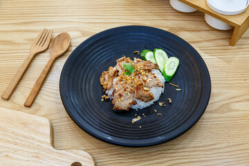 Stir-Fried Pork with Garlic and pepper with cooked thai jasmine rice in black plate, popular Thai Street food.
