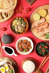 Composition with delicious Chinese dishes and decor on red background