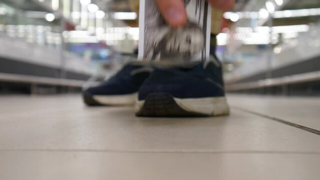 Close-up of a lost hundred dollar bill lying on the floor of a supermarket and a random man finds it