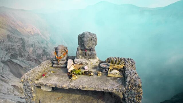 Ancient stone statue of Ganesha stands on a top of volcano Bromo