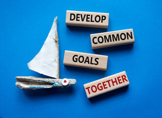 Develop common Goals Together symbol. Concept words Develop common Goals Together on wooden blocks. Beautiful blue background with boat. Business concept. Copy space.