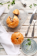 Tasty meat pot pies on light wooden background © Pixel-Shot