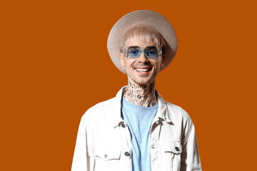 Young tattooed man in stylish sunglasses on color background