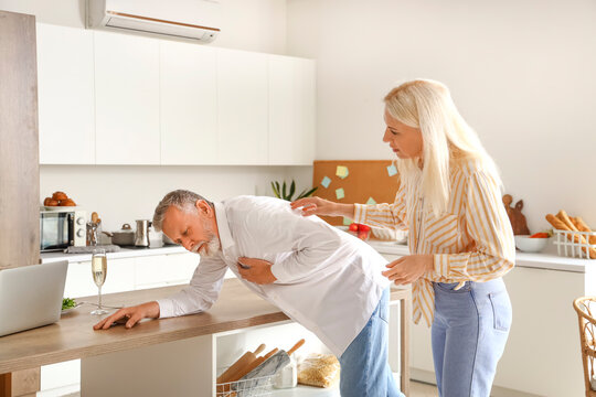 Mature woman and her husband having heart attack in kitchen