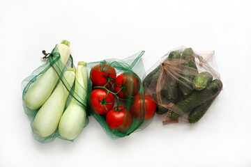 Eco bags with different fresh vegetables on white background