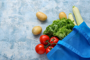 Eco bag with different fresh vegetables on blue background