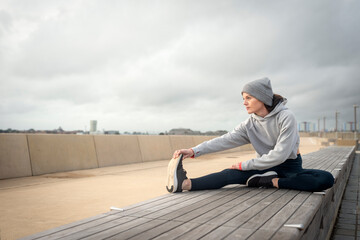 Fototapeta na wymiar Sporty woman doing leg stretching exercises, outside. Outdoor workout.
