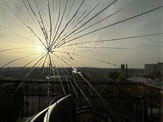 Cracks in a double glazed window. Cracked glass in a window against the background of the sun. Broken window indoors.