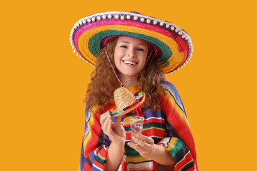 Happy Mexican woman with tequila on yellow background