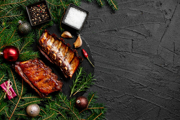 Christmas grilled pork ribs on a background of a Christmas tree and Christmas toys with copy space for your text