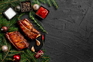Christmas grilled pork ribs on a background of a Christmas tree and Christmas toys with copy space...