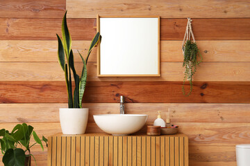 Wooden cabinet with sink, houseplant and mirror in interior of modern restroom
