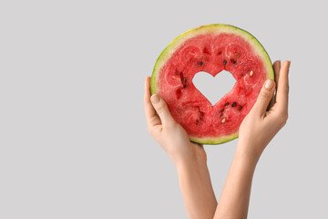Woman holding slice of ripe watermelon with heart on white background
