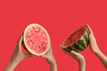 Female hands with halves of ripe watermelon on red background