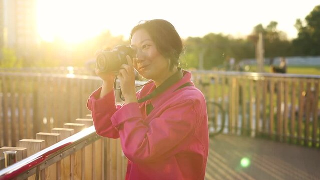Asian woman use of digital camera to take photo in city in the evening. asian traveler taking a photo at sunset. Solo travel concept.