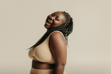 Voluptuous young African woman in underwear radiating joy and self-love on studio background