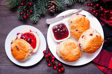 Fresh Cranberry scones with jam. Overhead view table scene on a dark wood background. Christmas...