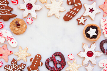 Christmas baking frame with a variety of cookies and sweet treats. Above view on a white marble...
