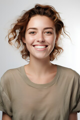 A girl in a plain t-shirt, isolated, portrait of a beautiful young brunette model woman laughing and smiling with clean teeth, excited and surprised expression on white background
