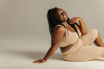 Joyful plus curvy African woman in sportswear radiating self-love  - obrazy, fototapety, plakaty