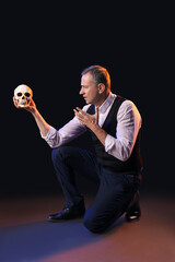 Mature actor with skull on dark background