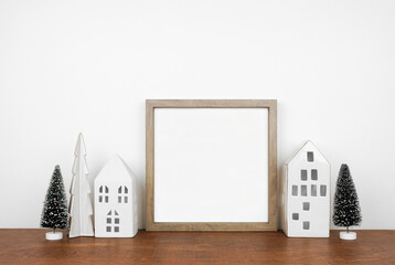 Christmas mock up with wooden frame, trees and white house decor. Square frame on a wood shelf...