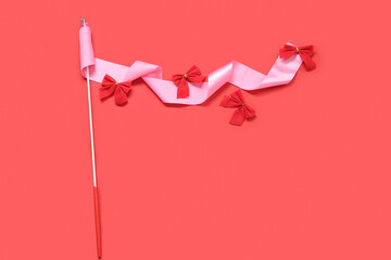 Gymnastics ribbon with Christmas bows on color background