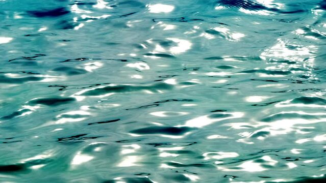smooth flowing water wave of a river with sunlight on water surface, slow motion close-up of fresh clean liquid texture, background for summer vacation holidays, beauty care and cosmetics