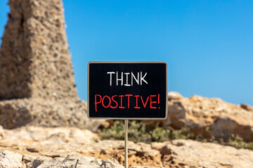 Think positive symbol. Concept words Think positive on beautiful chalk blackboard. Beautiful brown stone blue sky background. Business, motivational think positive thinking concept. Copy space.