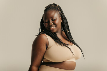 Attractive African plus size woman in underwear radiating self-love on studio background - obrazy, fototapety, plakaty