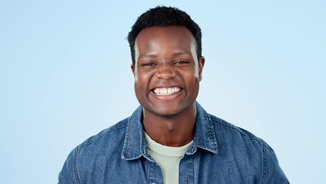 Happy, wink and face of black man laughing in studio for funny, comic or good mood on blue background. Emoji, portrait and African male model with humor, comedy and positive mindset or fun attitude