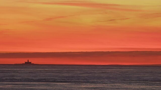 Lighthouse on horizon at red sunset