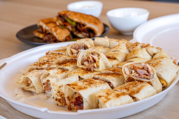 Pieces of shawarma on wooden table with dips and arranged on white plate