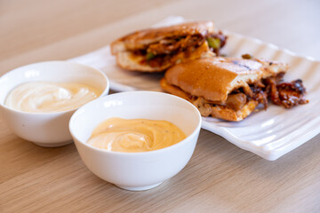 Italian pieces of shawarma full of peppers and BBQ sauces with chicken on wooden table with dips