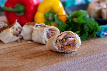 Shawarma pieces on wooden table with sweet peppers in the background and knife