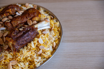Plate of meat and rice topped with almonds on wooden table with top view