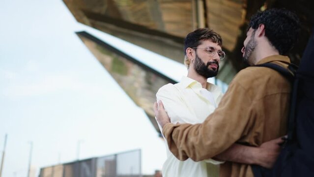 Two gay men in tender, intimate moment, one whispers affectionately into the other's ear, LGBT male partners smiles expressing comfort and joy in close embrace. Couple symbolizing love and acceptance