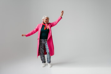 Full length of elegant senior woman in fashionable clothing radiating self-love while dancing 
