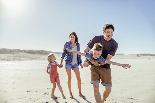 Young family of four having fun at the beach
