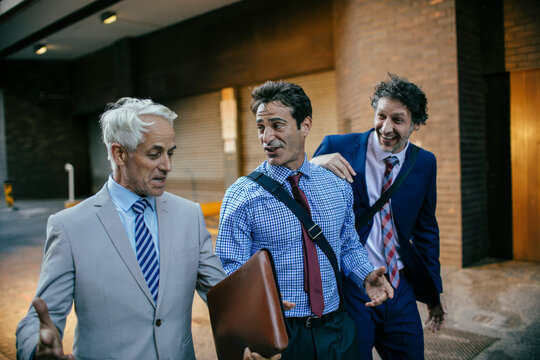 Three businessmen talking on the street and walking to work